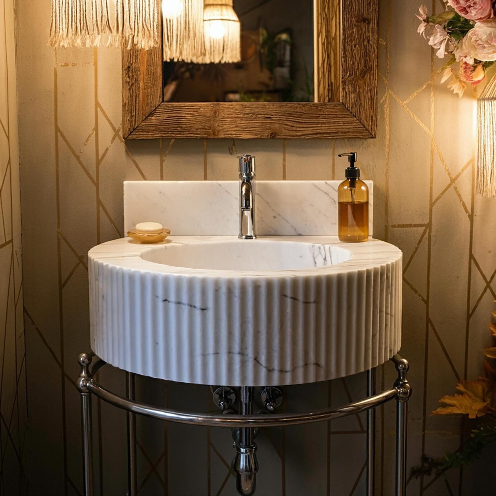 A fluted Carrara marble sink with a chrome base enhances the warm, elegant ambiance of a luxury powder room.