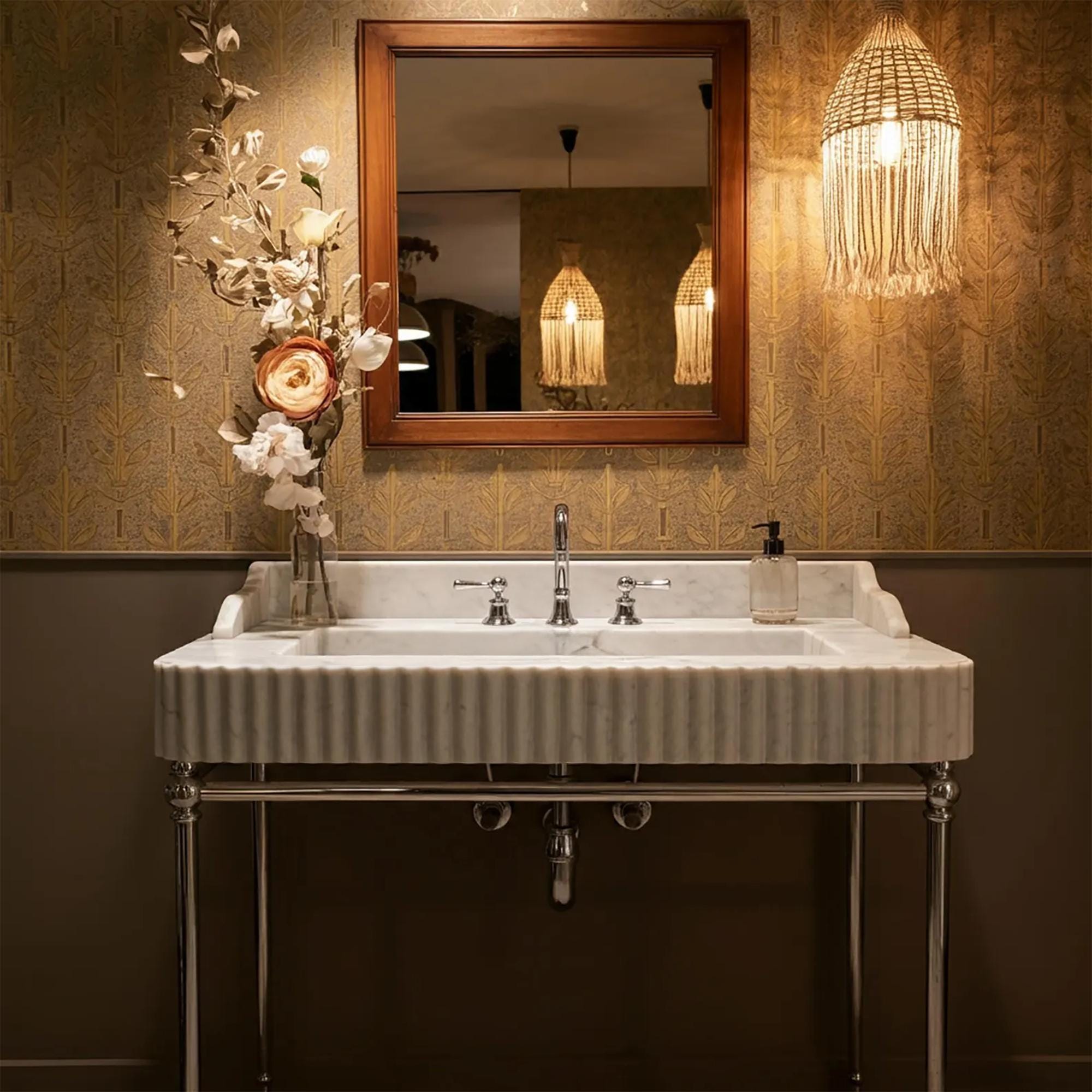 A luxurious Carrara marble double basin sink with fluted edges and chrome legs, styled in a classic bathroom setting.