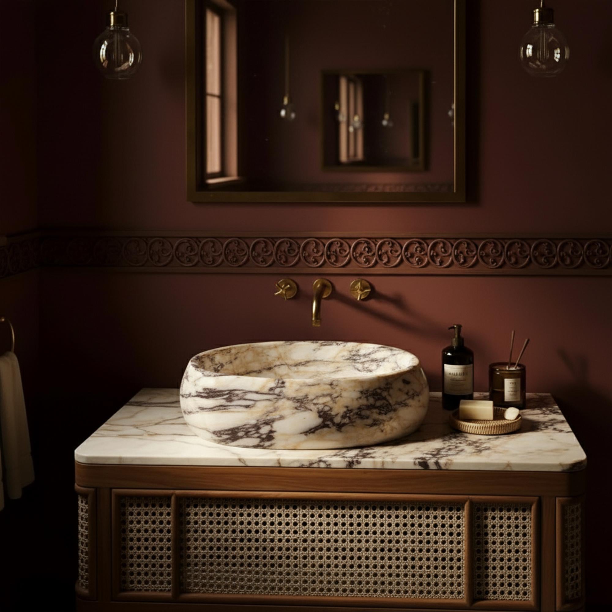 A handcrafted marble sink with rich veining sits atop a vintage-style rattan vanity, perfect for elegant interiors.