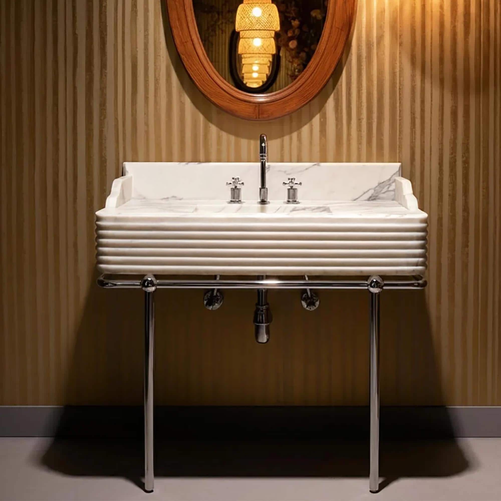 This white Carrara marble sink features fluted edges and a bold veining pattern, set atop a sleek chrome frame.
